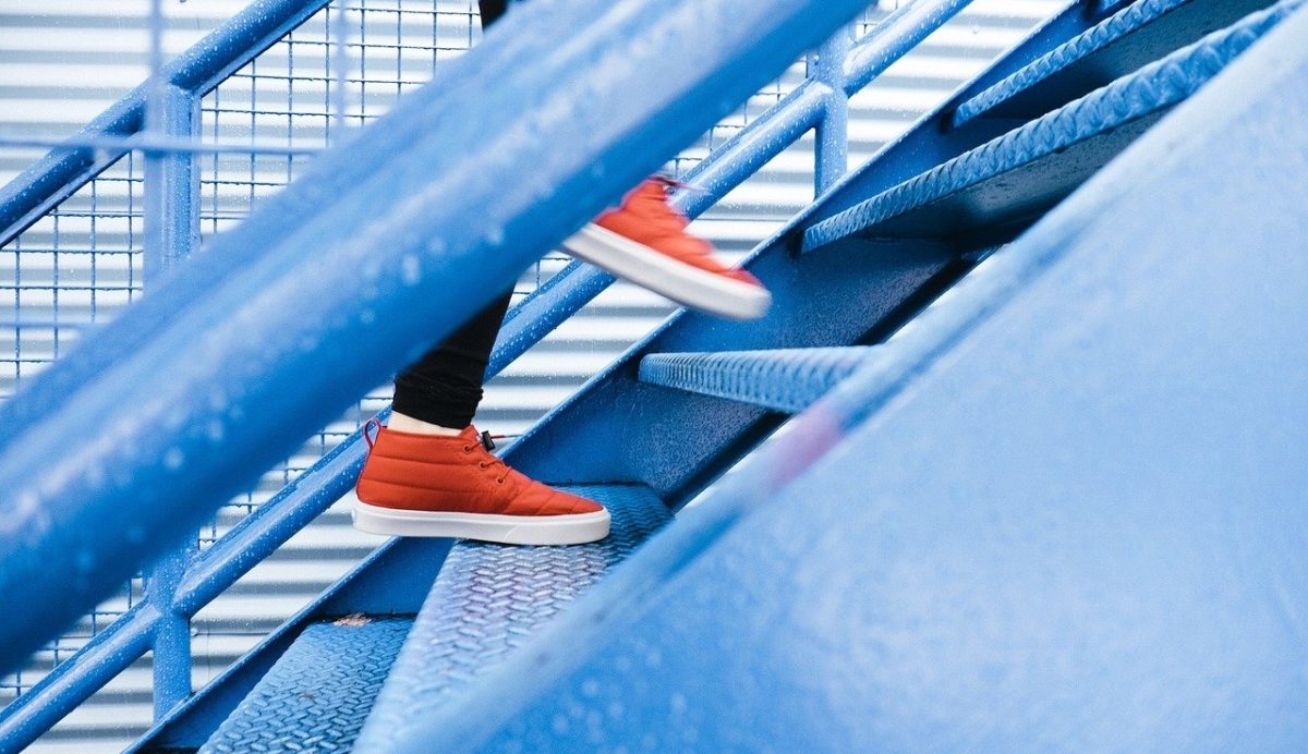 Photography of person with red trainers walking up a staircase