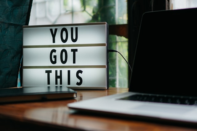 Laptop next to an illuminated sign reading 'You got this'
