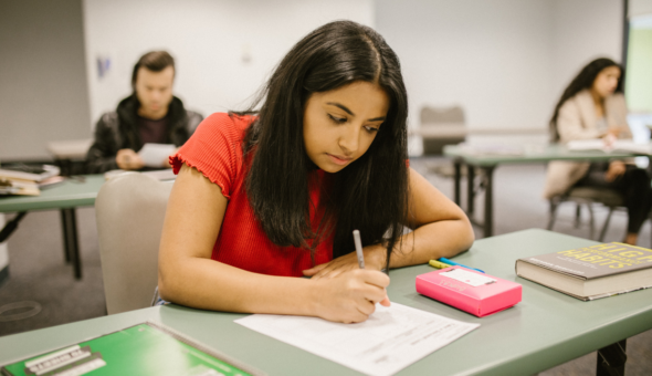 University students sitting at desks taking an invigilated in-person examination in an exam room.