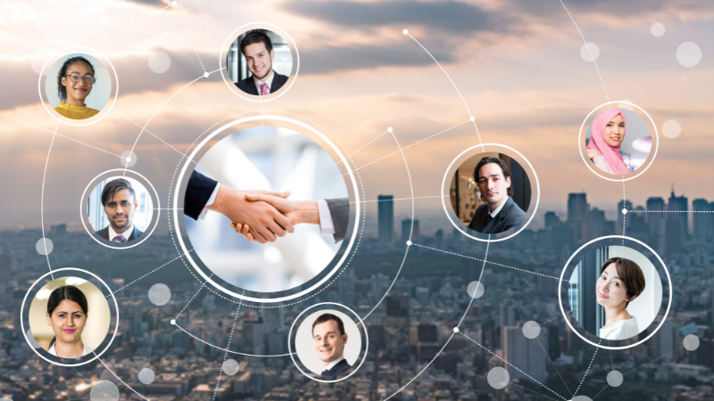 Headshots of people from different backgrounds using intercultural skills to connect with each other and work together effectively in a global network. In the background is a big city with lots of skyscrapers. There's a handshake in the centre of the image representing commercial success.