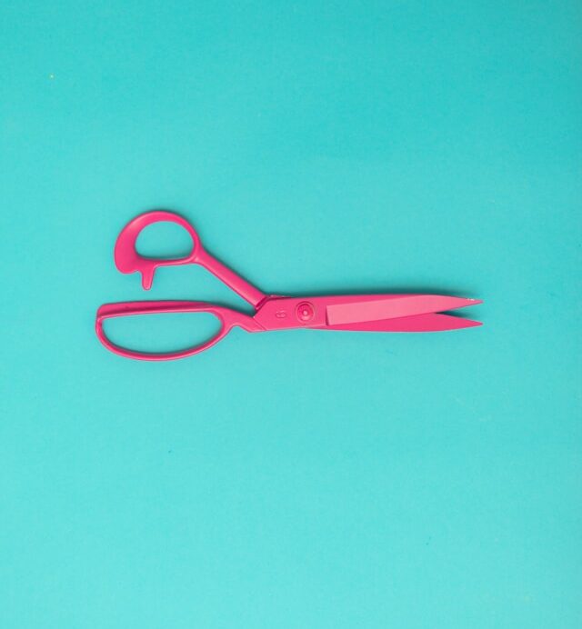 Pink scissors on a turquoise background