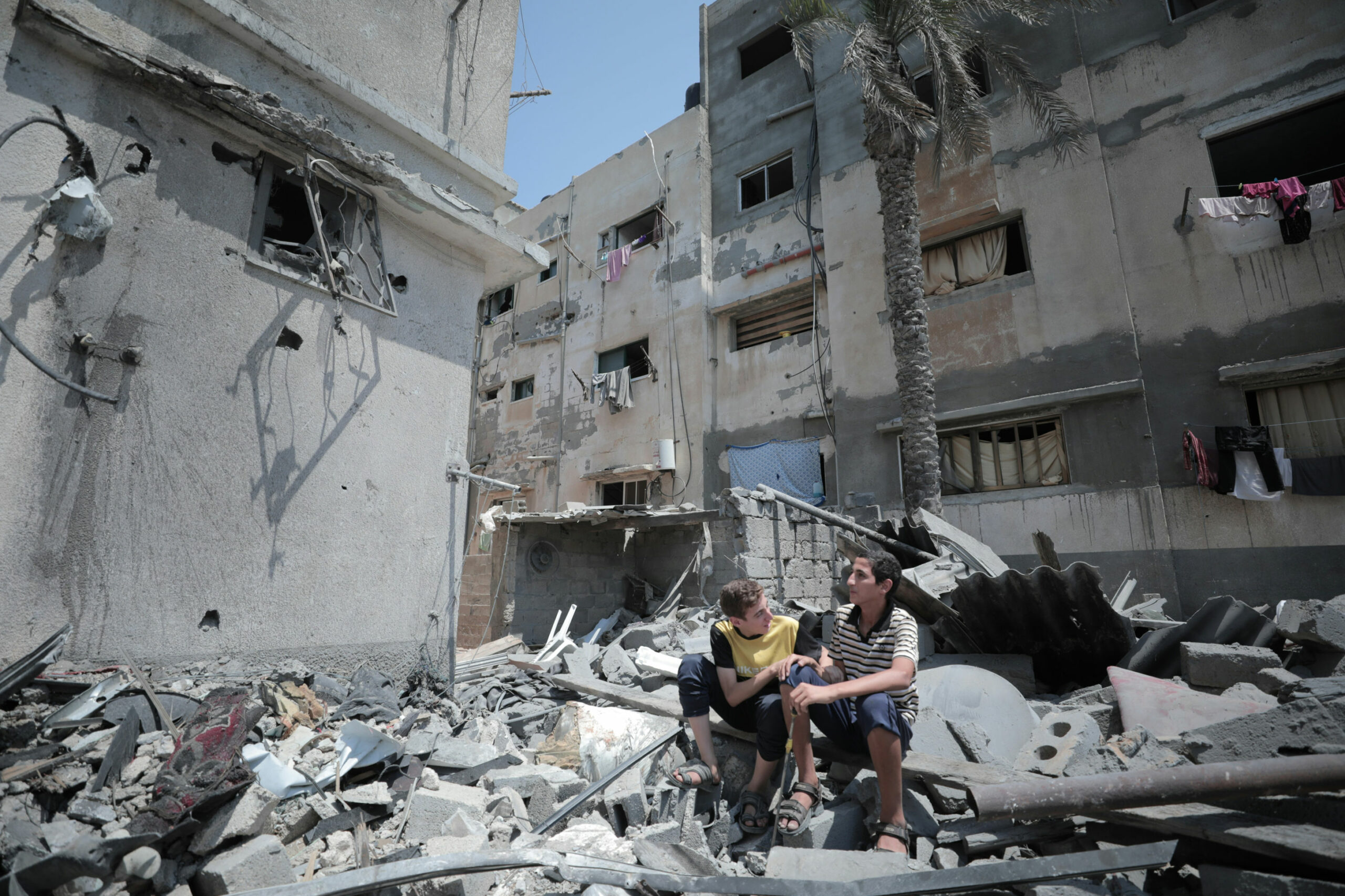 Two boys sat on a mound of rubble in a demolished neighbourhood | Photograph by Mohammed Ibrahim