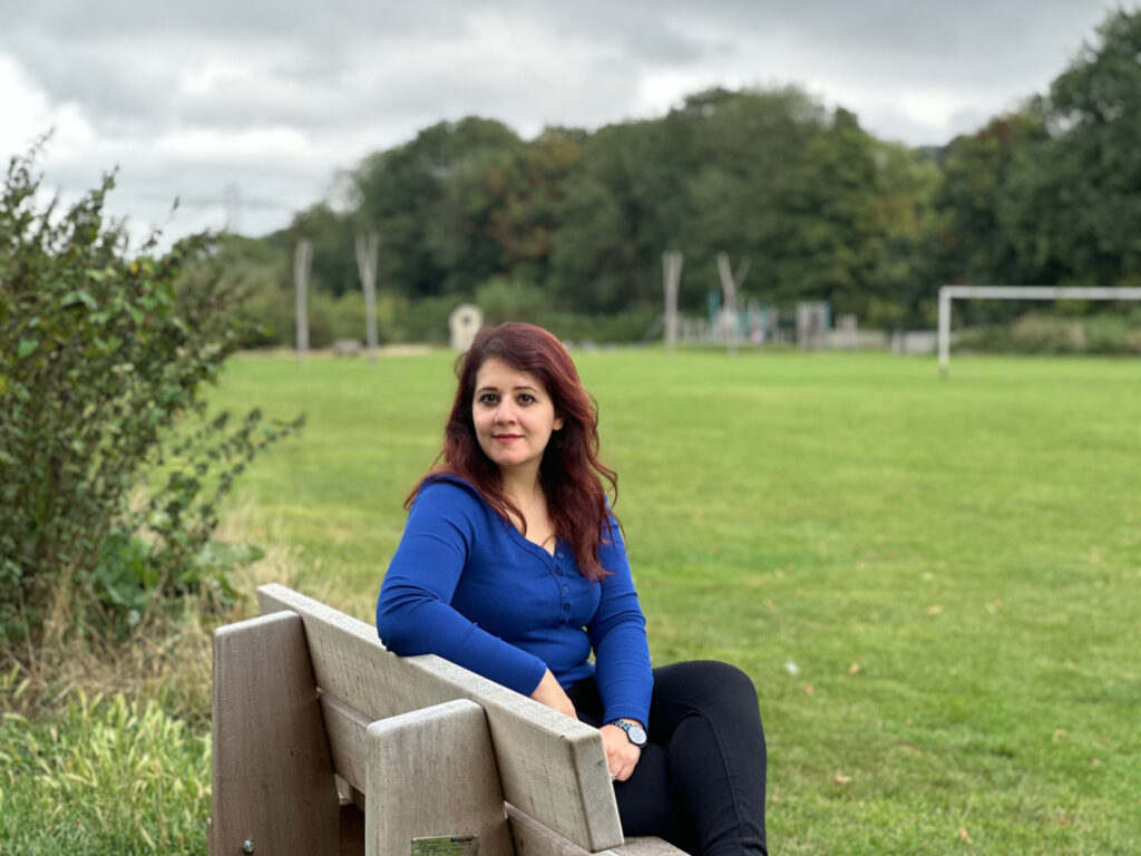 PhD student Zina Abdulla sat on bench in field