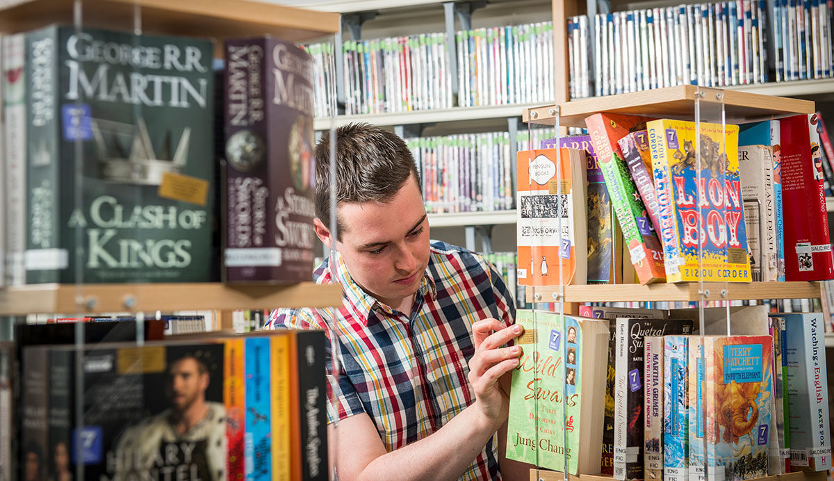 A man selects a book from a book carousel in a library