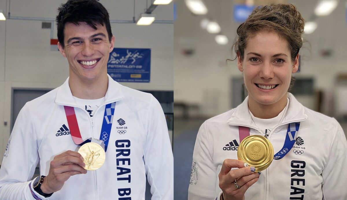 A man and a woman standing in a sports hall, each holding an Olympic gold medal.