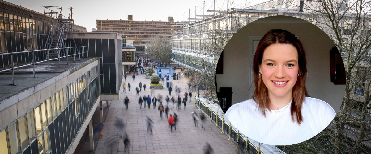 Brunette white woman smiling against a backdrop of the University of Bath.