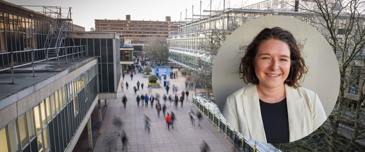 A smiling white brunette lady in a white blazer against a static background of Bath University's 'Parade' street.