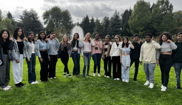 A large group of students posing by the University of Bath campus lake.