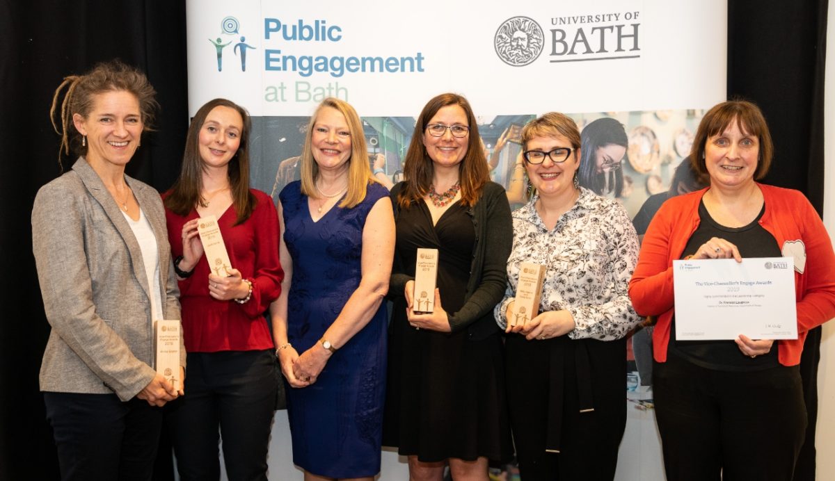 Five Vice-Chancellor's Award winners on a podium holding their awards