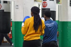 Rear view of a sport coach instructing a participant in a boxing gymnasium standing side-by-side