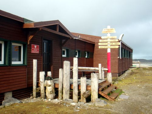 Front entrance to the Polish Polar Station. The arrows point to features of interest: Biegun (North Pole = 1,452 km) = , Arctowski (South Pole) = 16,252 km, Longyearbyen (the nearest settlement) = 136 km. The mast is decorated with a knitted Polish flag: guerilla knitting taken to extreme latitudes.