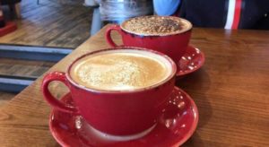 Two red coffee cups on a wooden coffee table