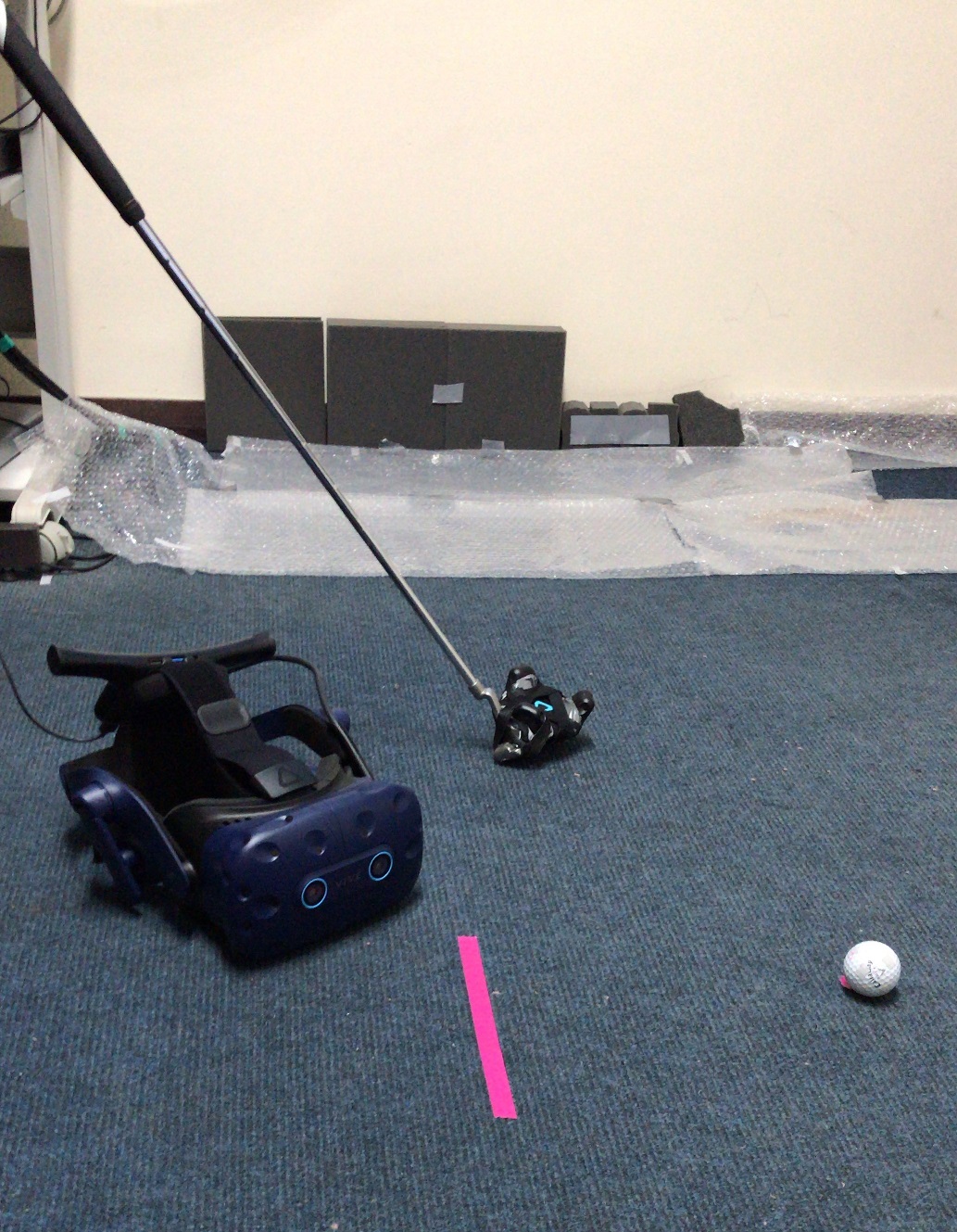 A virtual reality headset, golf club, and golf ball in a lab.