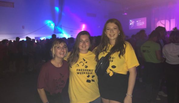In the Freshers Week arena with my two female friends wearing our accomodation t-shirts. Mine was purple and my friends were in yellow.