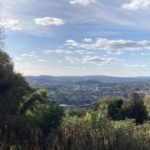View of Bath from mountain top, surrounded by grass, trees and hills.