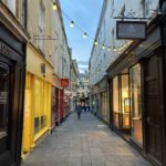 A street of shops, bright yellow, brown, and red, with street lights.