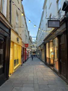 A street of shops, bright yellow, brown, and red, with street lights.