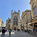 A sandstone church, known as the Bath Abbey, against a blue sky.