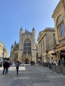 A sandstone church, known as the Bath Abbey, against a blue sky.