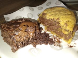 Half of a warmed up vegan brownie and half of a cookie sandwich from mrs potts cafe. 