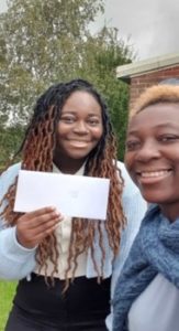 My mum and I smiling; I am holding up an envelope with my A Level results inside.