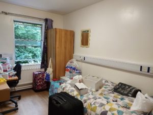 Photo of student accommodation including bed with items which are due to be unpacked after arrival