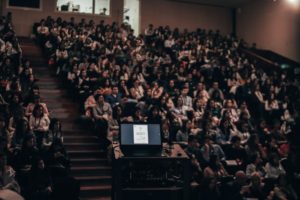 A darkened lecture hall filled with students from the lecturer's pov