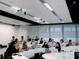 A group of students looking forward in a white lit room. 