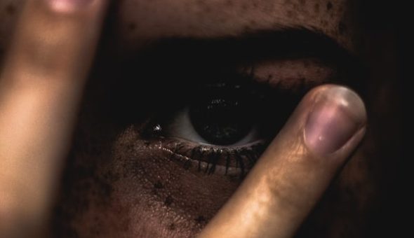 A woman looking scared through her fingers.