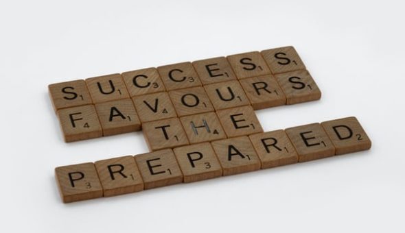 Scrabble tiles laid out on a white floor, reading "success favours the prepared".