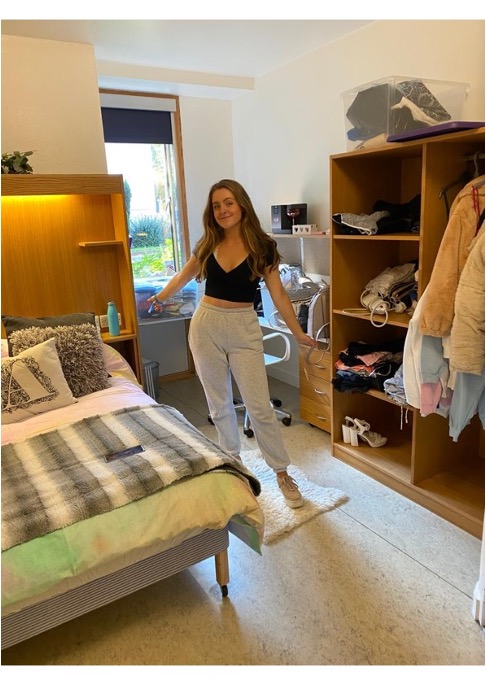Me stood in my student accommodation room surrounded by my bed, desk and open cupboards